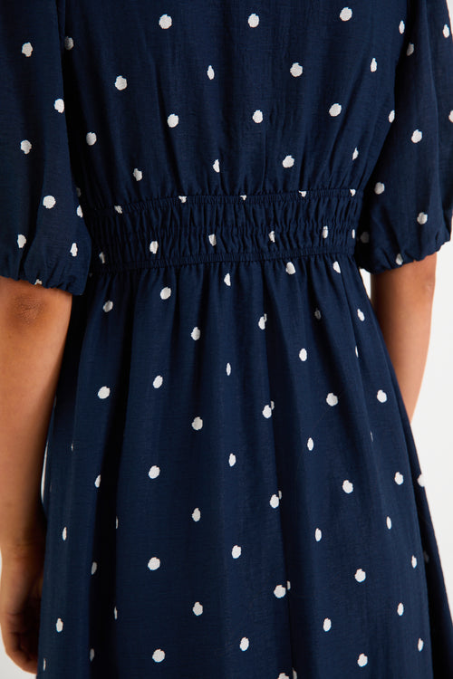 Model wearing a navy polka dot maxi dress with a V neckline, flutter sleeves and an elasticated waist