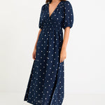 Model wearing a navy polka dot maxi dress with a V neckline, flutter sleeves and an elasticated waist