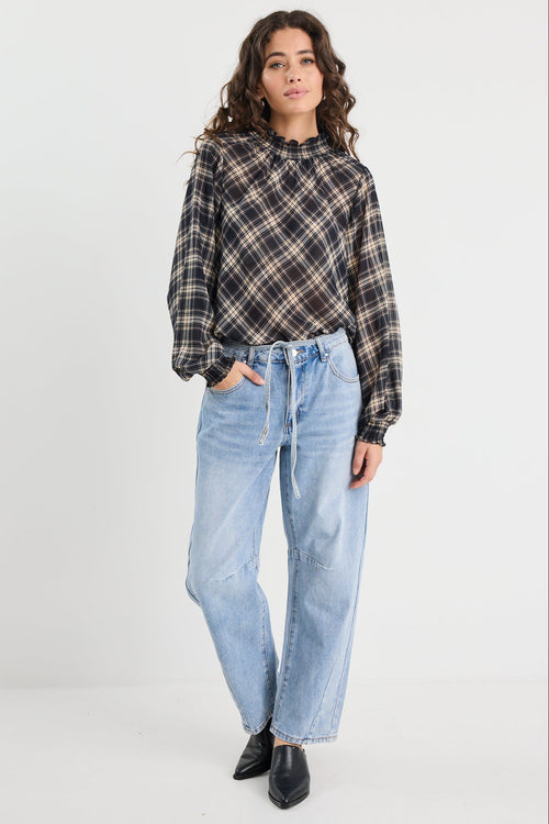 Person wearing a plaid shirt and light blue jeans on a white background