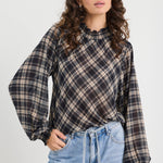 Woman wearing a plaid shirt and jeans against a white background