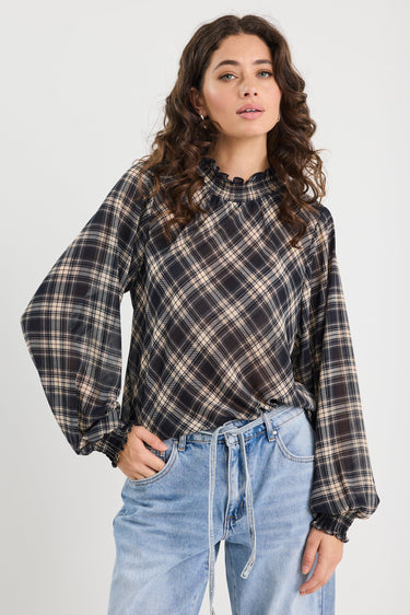 Woman wearing a plaid shirt and jeans against a white background