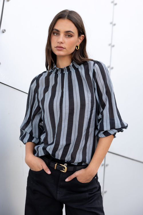 Woman wearing a black and gray striped blouse with a white background