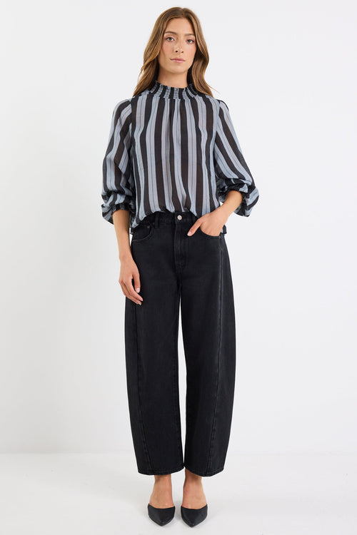 Woman wearing a black and white striped blouse and black pants on a white background