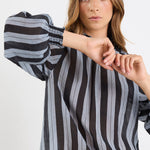 Woman wearing a black and gray striped shirt against a white background