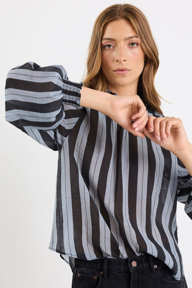 Woman wearing a black and gray striped shirt against a white background