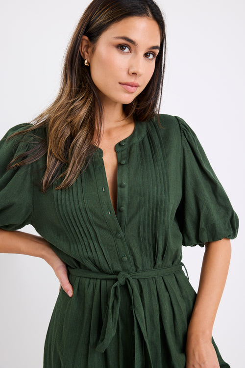 Woman wearing a forest green short sleeve midi shirt dress with puff sleeves, button front and waist tie.
