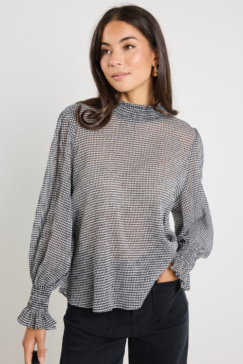 Model wears sheer black gingham long sleeve top