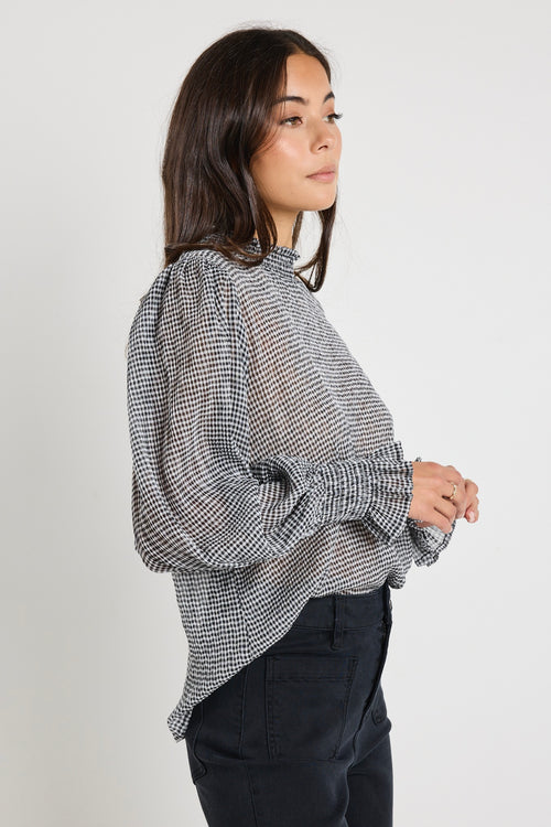 Model wears sheer black gingham long sleeve top