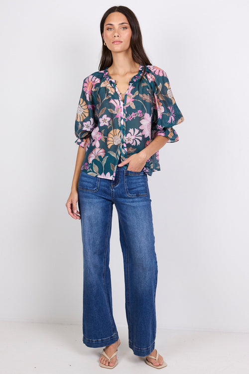 Woman wearing a floral blouse and blue jeans on a white background