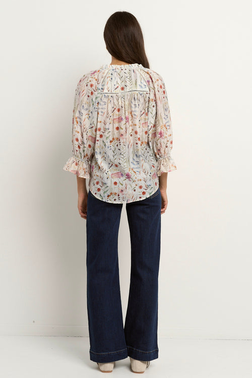 our model is wearing a cream floral blouse with dark blue jeans