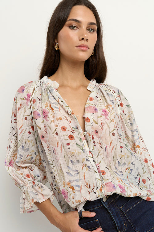 our model is wearing a cream floral blouse with dark blue jeans