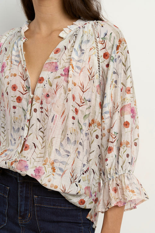 our model is wearing a cream floral blouse with dark blue jeans