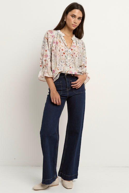 our model is wearing a cream floral blouse with dark blue jeans