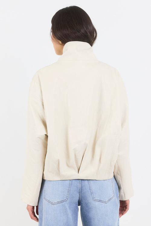 Person wearing a cream-colored sweater and light blue jeans on a white background