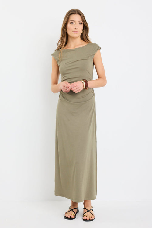 Woman wearing a sleeveless khaki midi dress with boat neckline and ruched side detailing, styled with black strappy sandals.