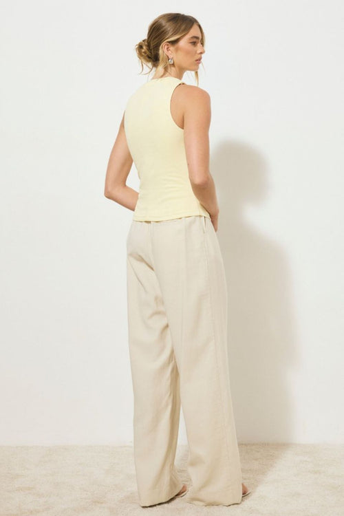 Lemon yellow sleeveless tank top with ruched bodice and centre band detail, styled with light beige wide-leg pants, worn by a model standing against a neutral background.