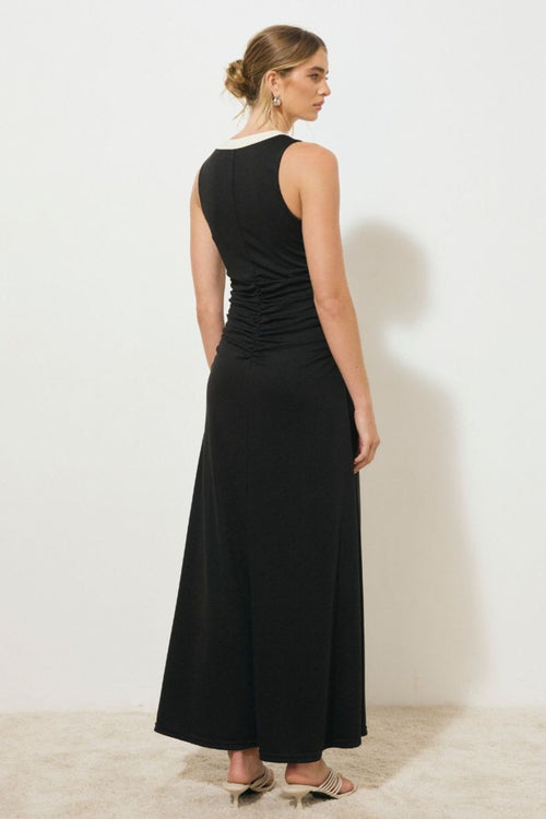 Black sleeveless midi dress with a low V-neckline, contrast cream band detail down the centre front, ruched bodice, and front hem split, worn by a model standing against a white background.