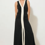 Black sleeveless midi dress with a low V-neckline, contrast cream band detail down the centre front, ruched bodice, and front hem split, worn by a model standing against a white background.