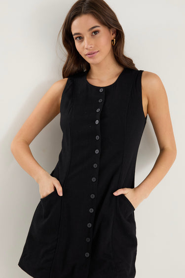 model wears a black button up mini dress with sneakers