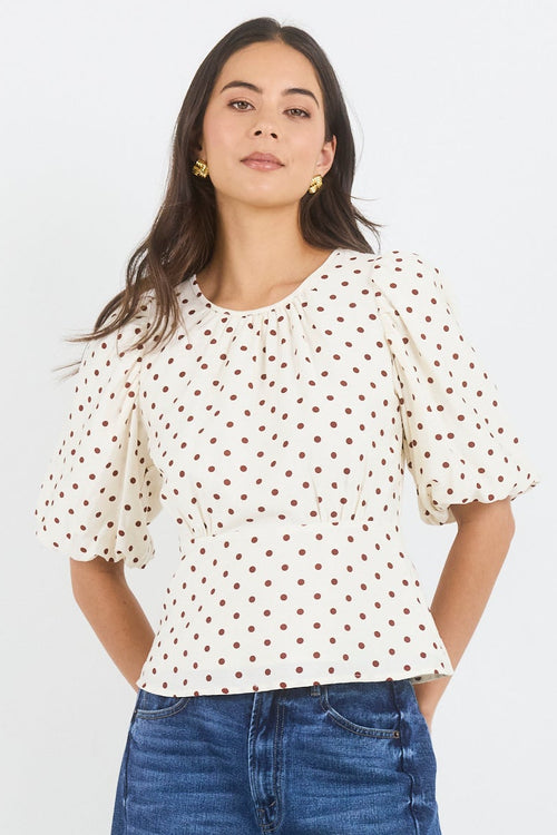 Woman wearing a polka dot shirt and blue jeans on a white background