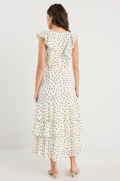 Woman wearing a white dress with black polka dots on a plain background