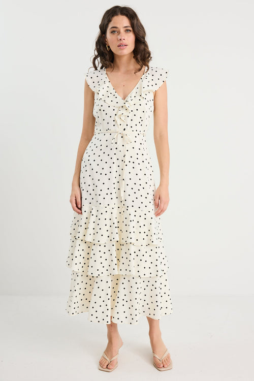 Woman wearing a white dress with black polka dots on a white background