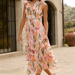 Woman in a floral dress walking on a stone path in front of a stone building.