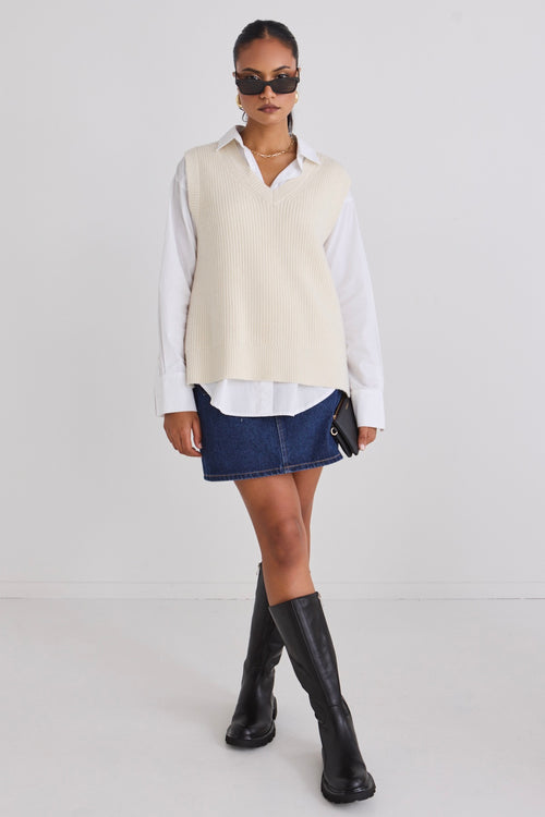 Model wears a knit vest with a white shirt 