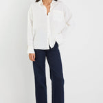Woman wearing a white blouse and dark blue jeans on a white background