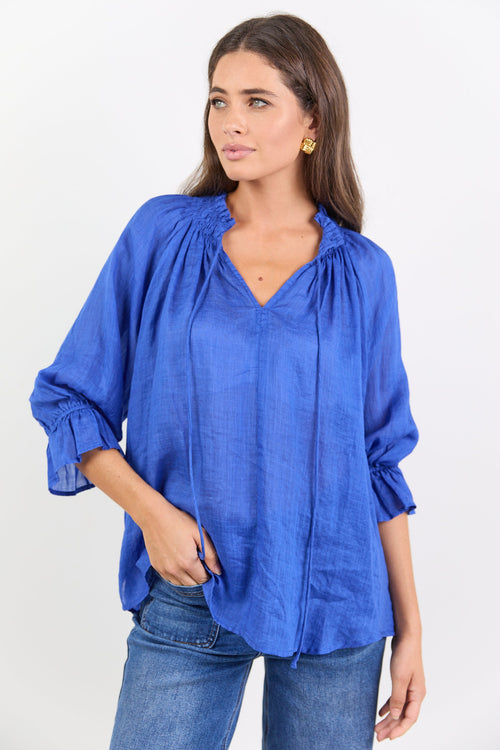 Woman wearing a blue blouse with ruffled sleeves on a white background