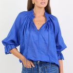 Woman wearing a blue blouse with ruffled sleeves on a white background