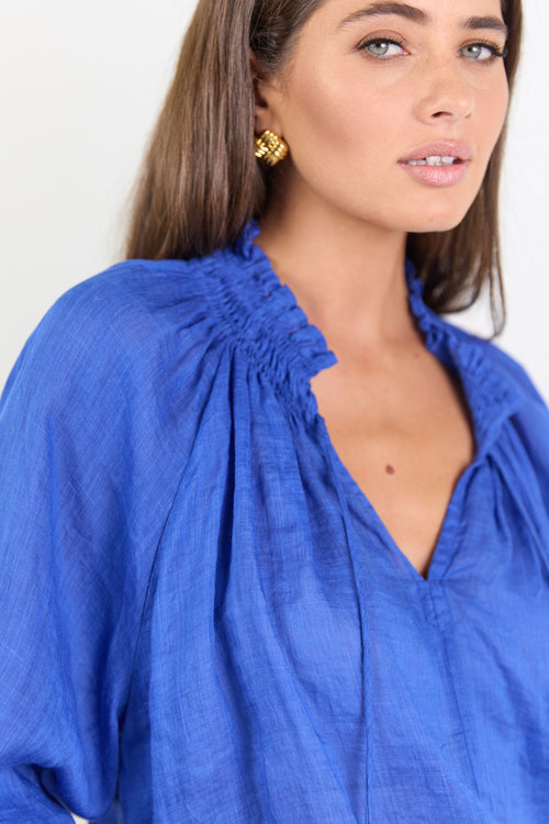 Woman wearing a blue blouse with a plain background