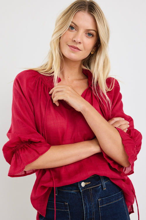 model wears a red blouse with denim jeans