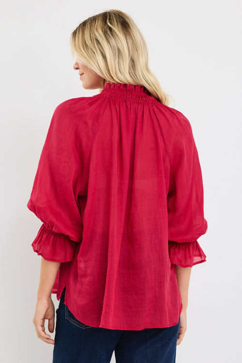 model wears a red blouse with denim jeans