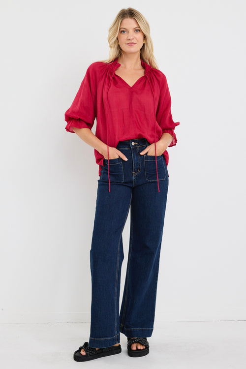 model wears a red blouse with denim jeans