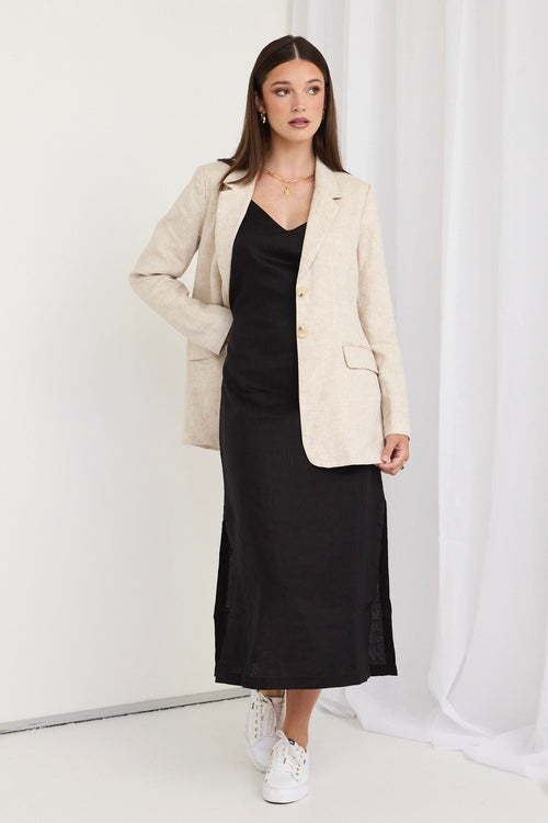 model wears black linen midi dress and beige linen blazer and white sneakers