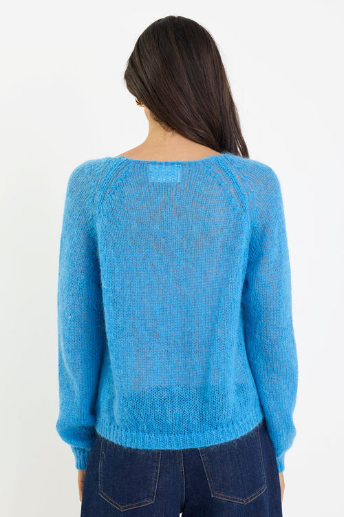 Person wearing a blue sweater and dark jeans on a white background