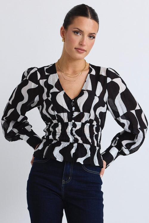 model wears a black and white print top