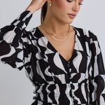 model wears a black and white print top