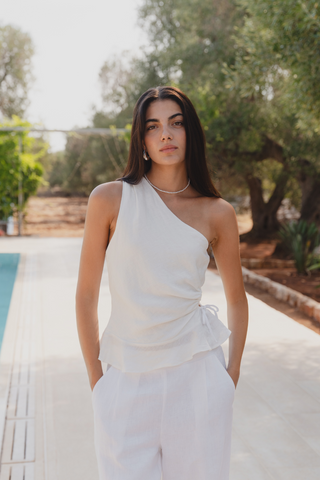 model is in a white top and white pants by a pool