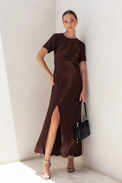 Model wears a chocolate brown short sleeve maxi dress with a side slit