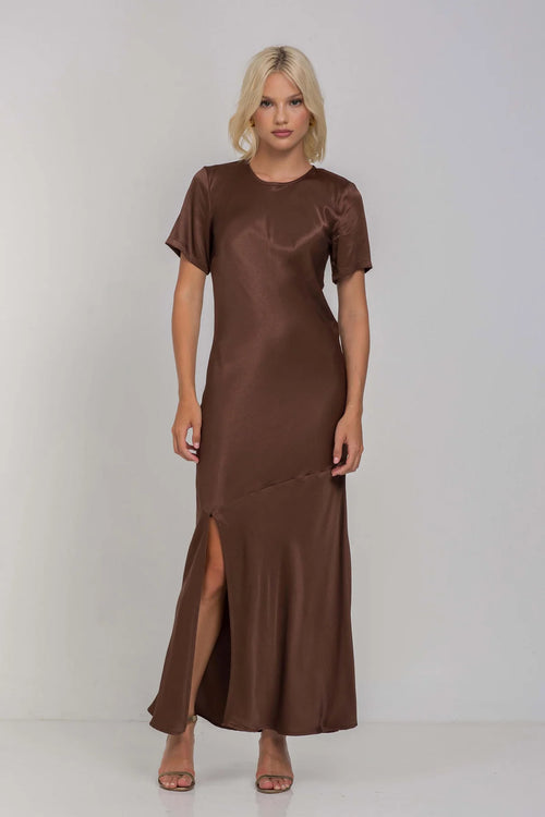 Model wears a chocolate brown short sleeve maxi dress with a side slit