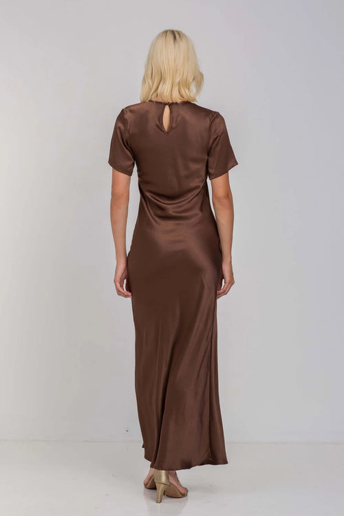 Model wears a chocolate brown short sleeve maxi dress with a side slit