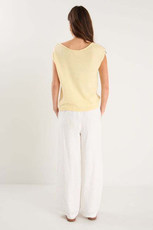 The model wears a yellow knit top with white pants