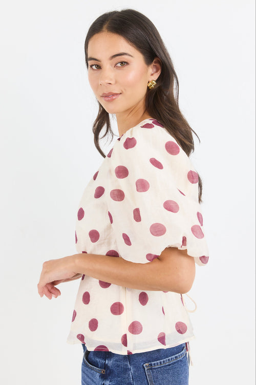Woman wearing a polka dot blouse with a plain background