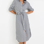 Woman wearing a black and white striped dress with a belt on a white background