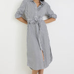 Woman wearing a black and white striped dress with a belt on a white background