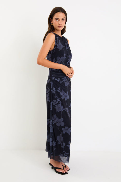 Model wearing a sleeveless midnight floral mesh maxi dress with gentle gathering at the waist and a slim, draped silhouette.
