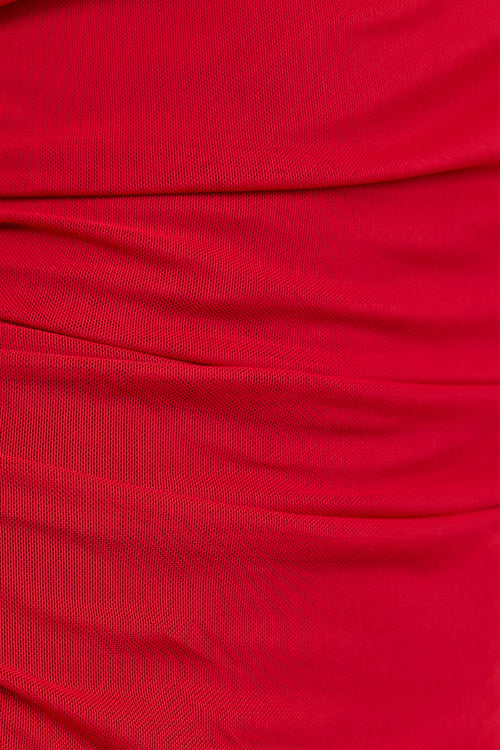 A close-up of draped red fabric with soft folds and a smooth texture.