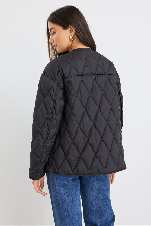 Person wearing a black quilted jacket on a white background